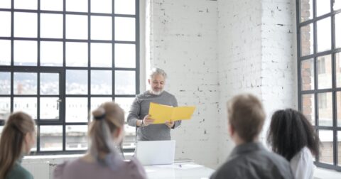 Homem a apresentar algo num caderno amarelo