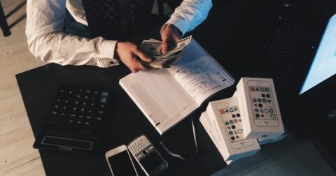 Pessoa a contar notas enquanto tira notas de vendas de telemóveis